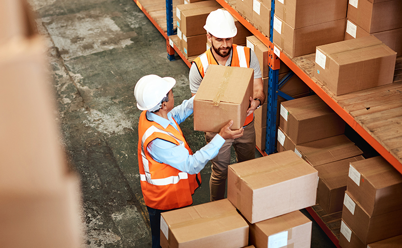 Two warehouse workers unloading boxes from shelves in a fulfillment center.